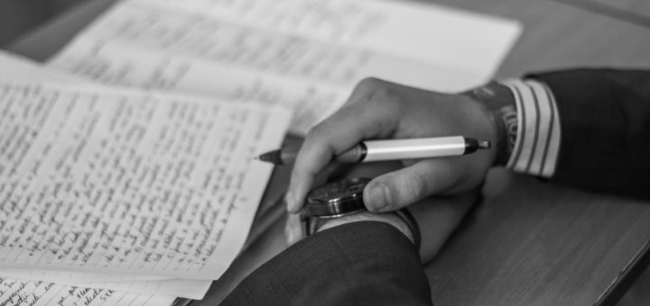 grayscale photography of person holding pen