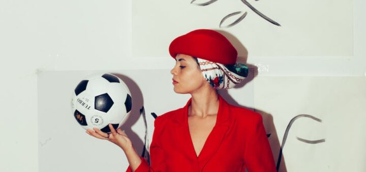 woman in red blazer holding white and black soccer ball